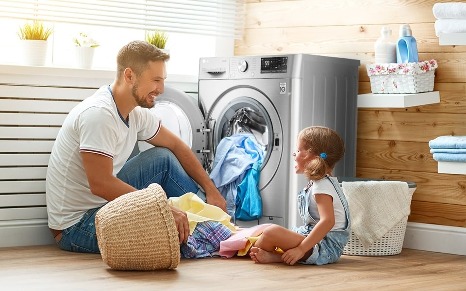 A person and a child sitting on the floor next to LG Dryer